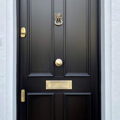 Antique brass dual door lock set on a 4-panel black door with matching Heritage Brass fittings — keyed alike for secure, coordinated access.